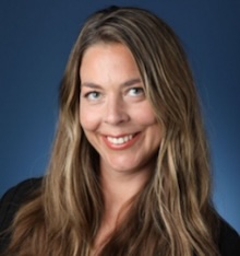 Woman with long brown hair smiling blue background
